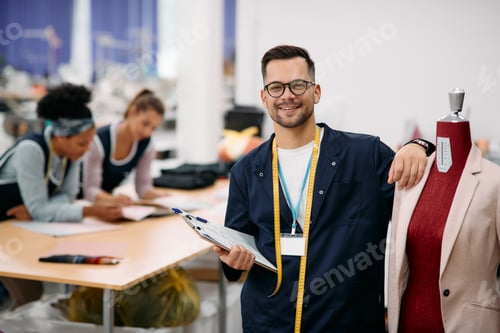 Preview: Portrait of young happy tailor at textile factory looking at camera.
