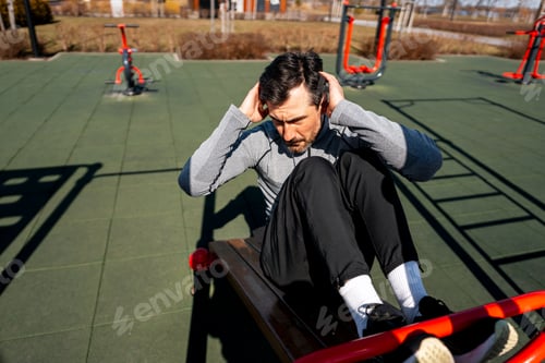 Preview: Man doing sit ups on outdoor fitness equipment