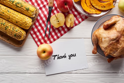 Preview: top view of pumpkin pie, turkey and vegetables served at white wooden table with thank you card for