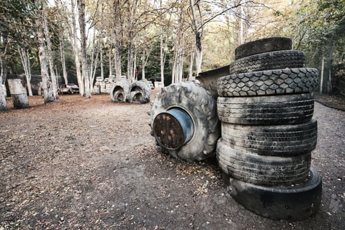 Preview: Old rusty barrels and damaged tires on a paintball base