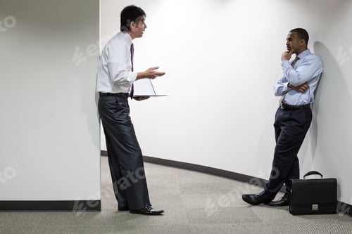 Preview: An asian businessman and a black businessman talking over an issue in an office