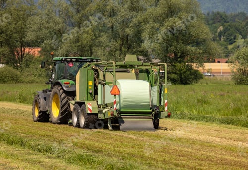 Preview: Tractor cultivating a field surrounded by green grass