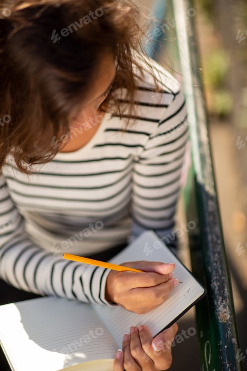 Preview: Top down young woman writing notes in diary