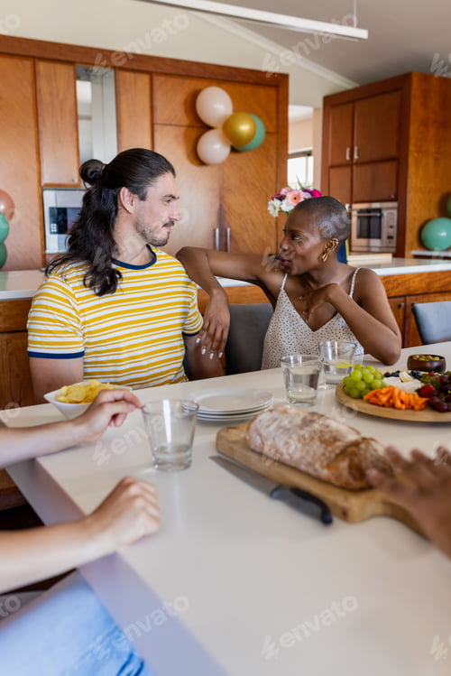 Preview: Friends enjoying casual conversation at home with snacks and drinks on table