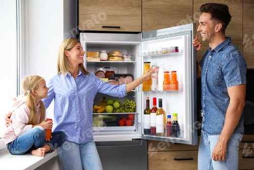 Preview: Happy family near refrigerator full of products in kitchen