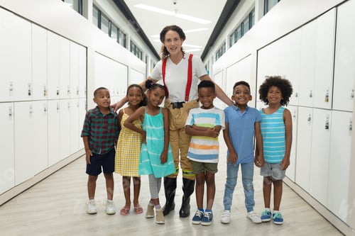 Preview: Portrait of african american students with young female caucasian teacher standing in corridor