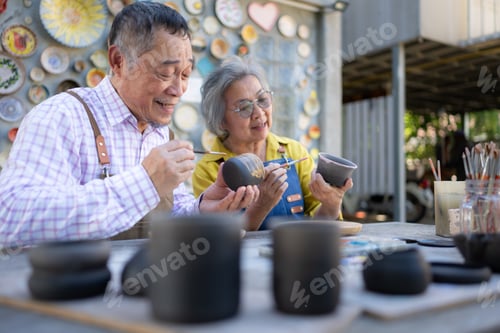 Preview: Asian retired couple is engaged in pottery making and clay painting activities.