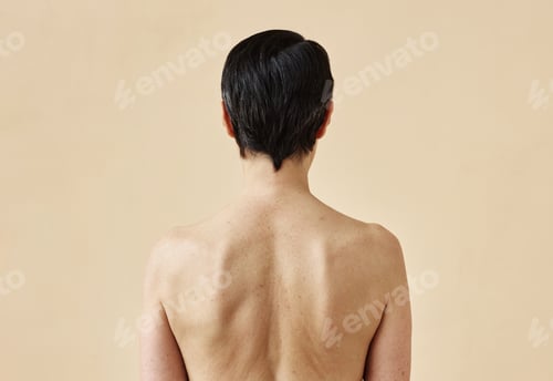 Preview: Woman with bare back standing against minimal beige background