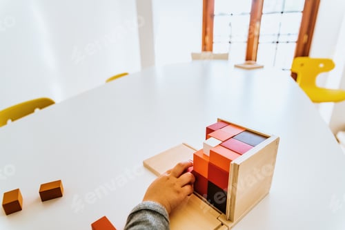 Preview: Hand of a student handling montessori material inside a classroom.