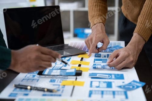Preview: ux developers and ui designers, data researchers brainstorm on tabletop mobile app interface wirefr