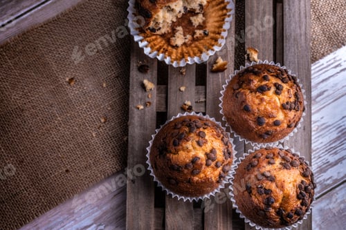 Preview: Top view of the freshly baked cupcakes with chocolate chips on a wooden tray