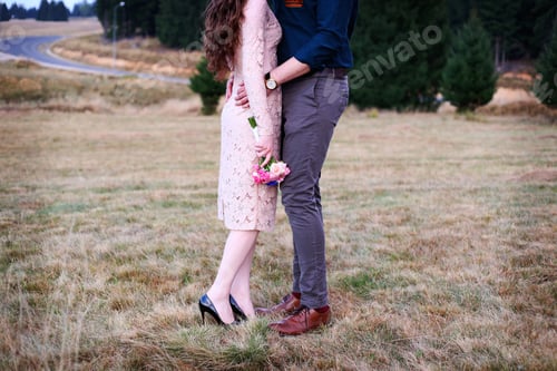 Preview: Couple embracing outdoors, no face. Holding flowers