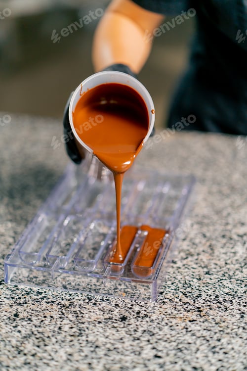 Preview: Melted hot chocolate is poured into a transparent chocolate mold for making natural candies