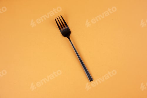 Preview: Above view of elegant metal fork on golden color background with free space