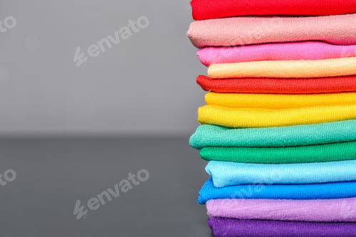 Preview: Stack of colorful t-shirts on table against gray background