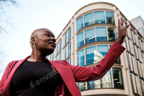 Preview: Businesswoman hailing a cab in front of modern office building