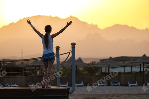 Preview: Happy woman relaxing outdoors on hotel deck on sea shore enjoying warm tropic evening.