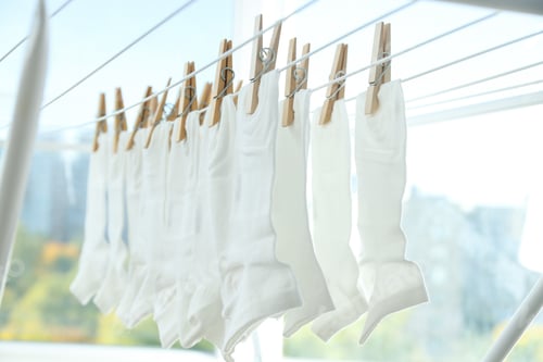 Preview: Wooden clothespins with white socks on the dryer