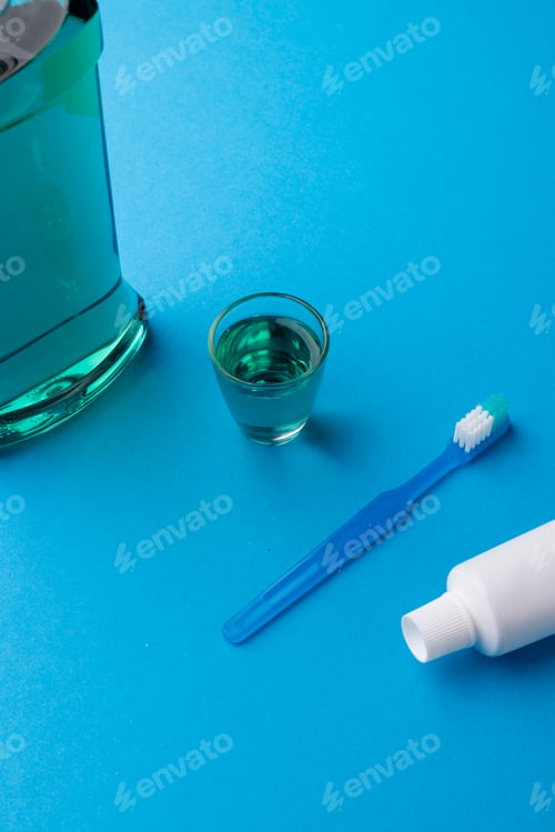 Preview: Vertical image of cleaning liquid, toothbrush and toothpaste on blue surface
