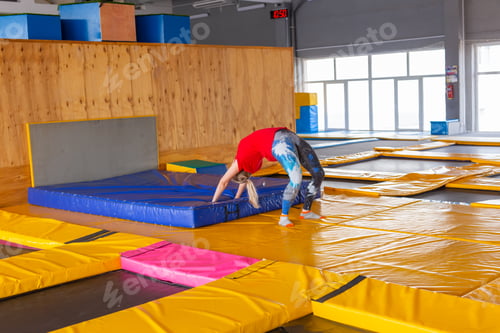 Preview: Young woman sportsman on a trampoline in fitness park and doing exercise indoors