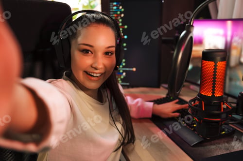 Preview: Smiling young woman gamer in headphones