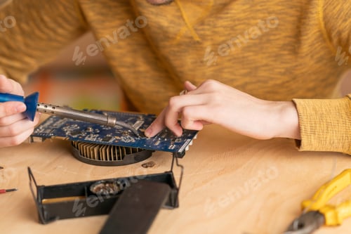 Preview: a young man solders a burnt-out microcircuit with a soldering iron