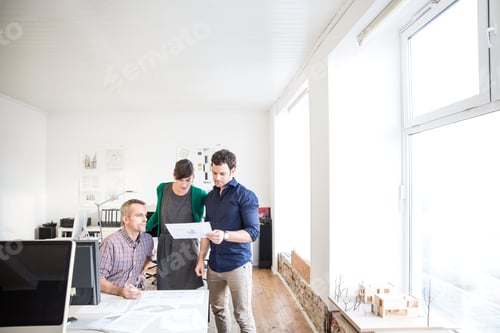 Preview: Colleagues at desk in office discussing paperwork