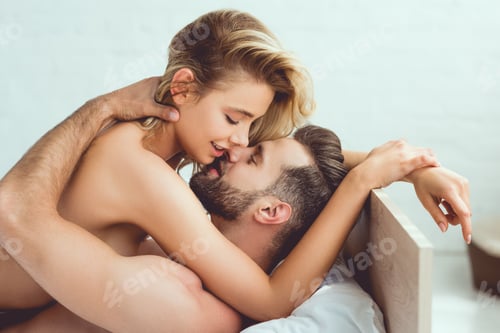 Preview: handsome young man embracing beautiful, sexy girlfriend while lying in bed