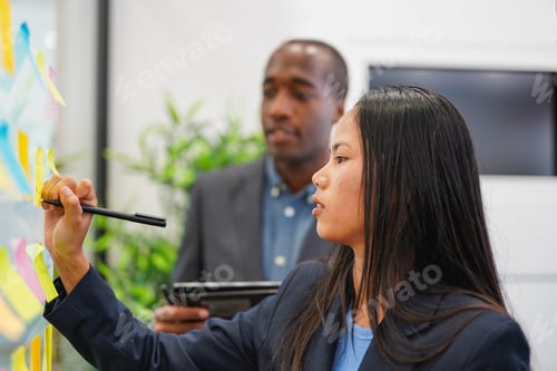 Preview: Asian business woman writing on a glass wall inside modern office