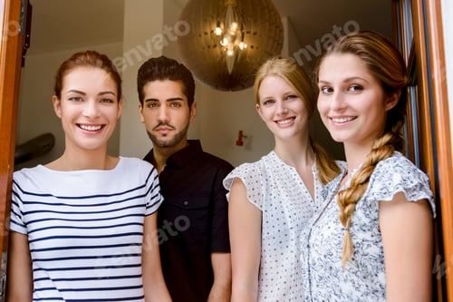 Preview: Four young adults smiling at the entrance of a house.
