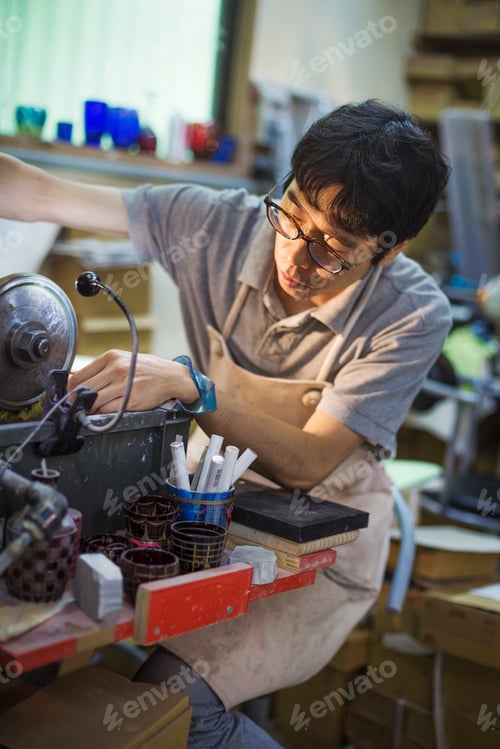 Preview: A craftsman at work in a glass maker's workshop, using a machine to etch glass.