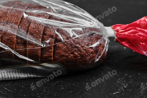 Preview: Sliced black rye bread in plastic bag on dark background