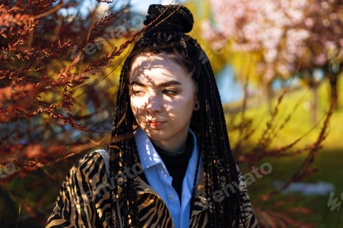 Preview: Young tender brunette girl with dreadlocks near herbal branch in front of her face. Portrait of a wo