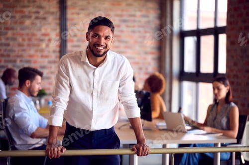 Preview: Portrait Of Smiling Businessman Standing In Busy Office