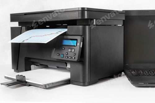 Preview: Printer works on a document as laptop sits nearby in a workspace setting