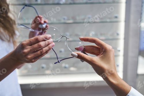 Preview: Optician hand giving glasses to woman in optical shop