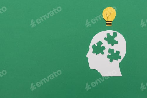 Preview: White Head Silhouette with Puzzle Pieces and Yellow Light Bulb on Green Background