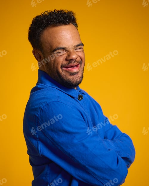 Preview: Studio Portrait Of Smiling Man With Down Syndrome Standing Against Yellow Background