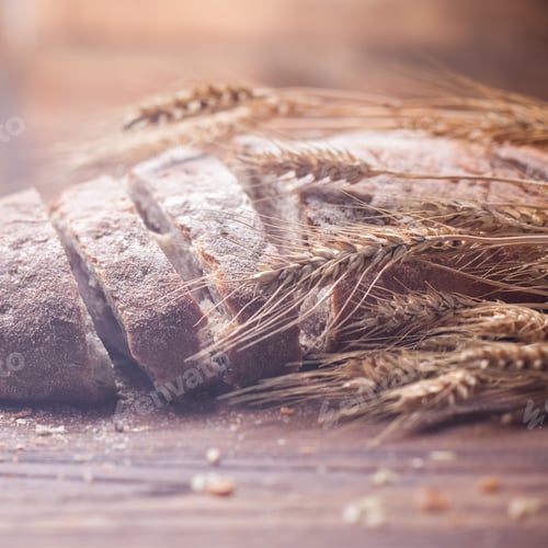 Preview: Bread and wheat on wooden table, shallow DOF
