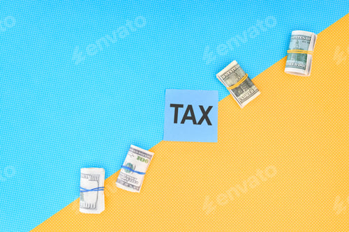 Preview: top view of money rolls and card with word 'tax' on blue and yellow background
