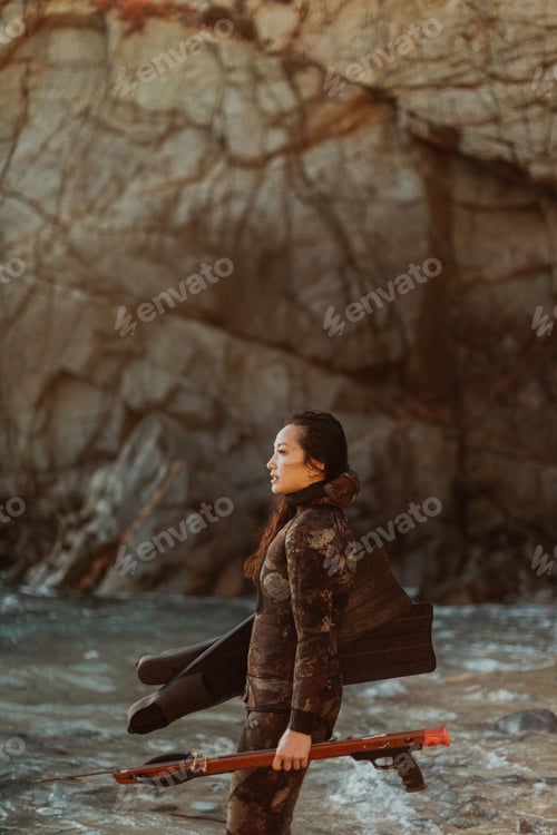 Preview: Woman with flippers and speargun on beach, Big Sur, California, United States