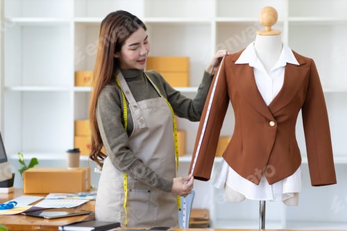 Preview: Fashion designer working in workshop measuring shirt sample on dummy.