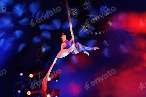 Vista previa: Aerialist performs a dangerous trick on a fabric high under dome of the circus under the spotlight.