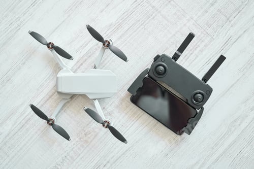 Preview: New modern drone with remote control panel placed on floor