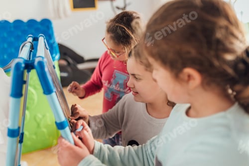 Preview: Girls Drawing Together Indoors at Easel