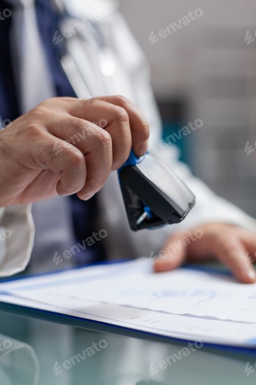 Preview: Hand of general practitioner using medical stamp on prescription paper