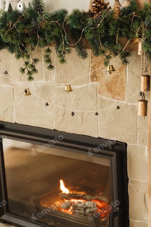Preview: Rustic wicker basket with spruce branches, vintage bells and lights on background of fireplace