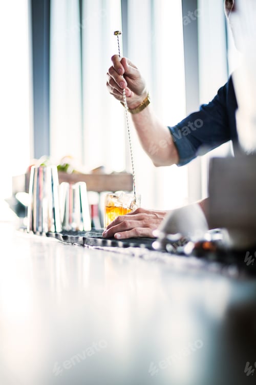 Preview: Cropped image of bartender stirring whisky in glass