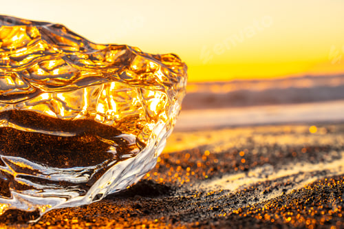 Preview: Clear ice at sunrise on Diamond Beach next to Jokulsarlon in winter in Iceland