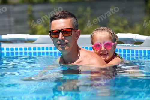 Preview: Father in sunglasses swims in the pool with his daughter.